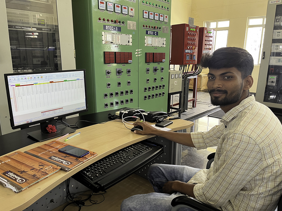 Engineer in Pavagada Solar Park substation, sitting by his computer adorned with a flower.